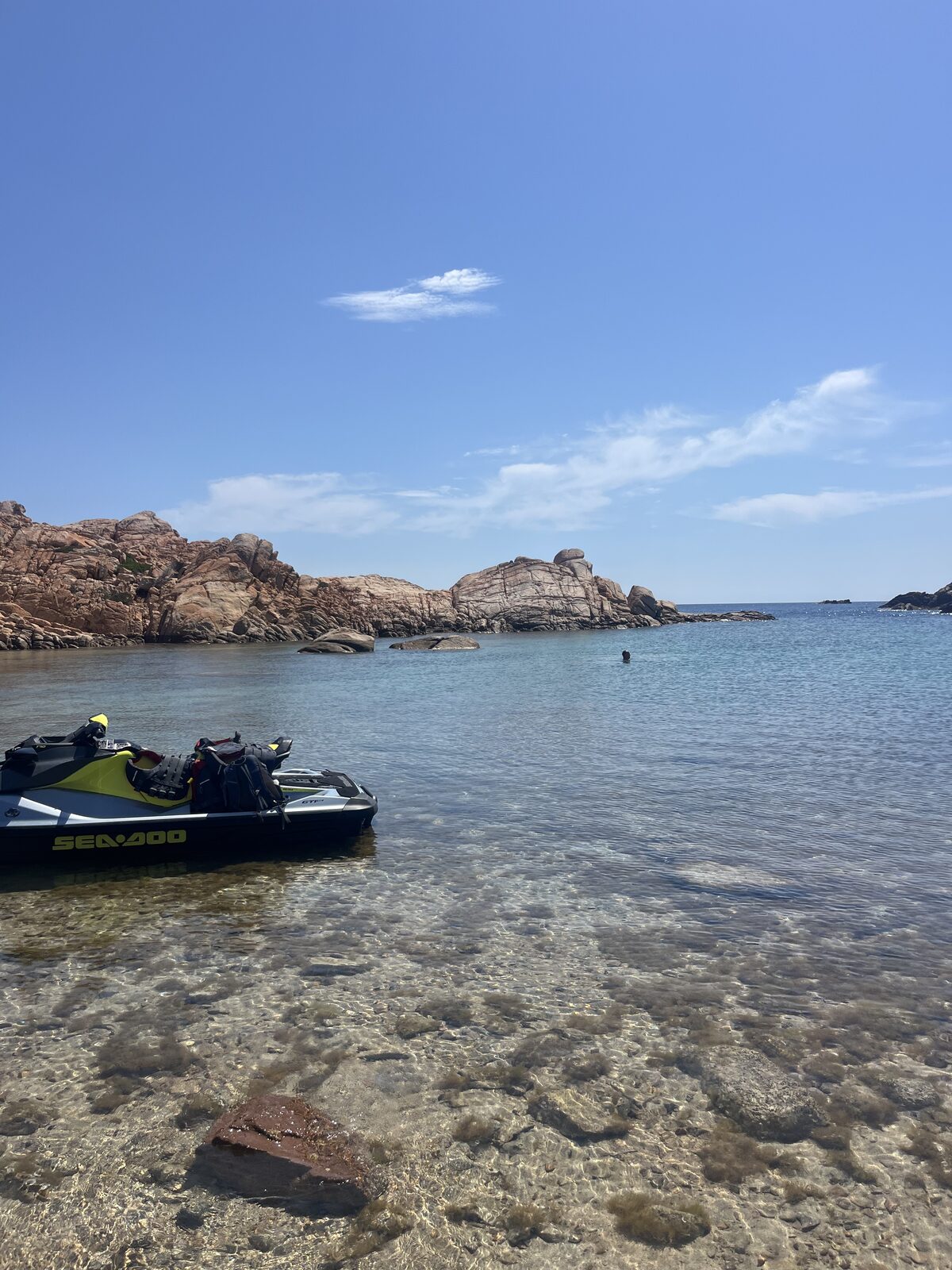 Moto d'acqua in una cala nascosta tra le rocce rosa della Sardegna